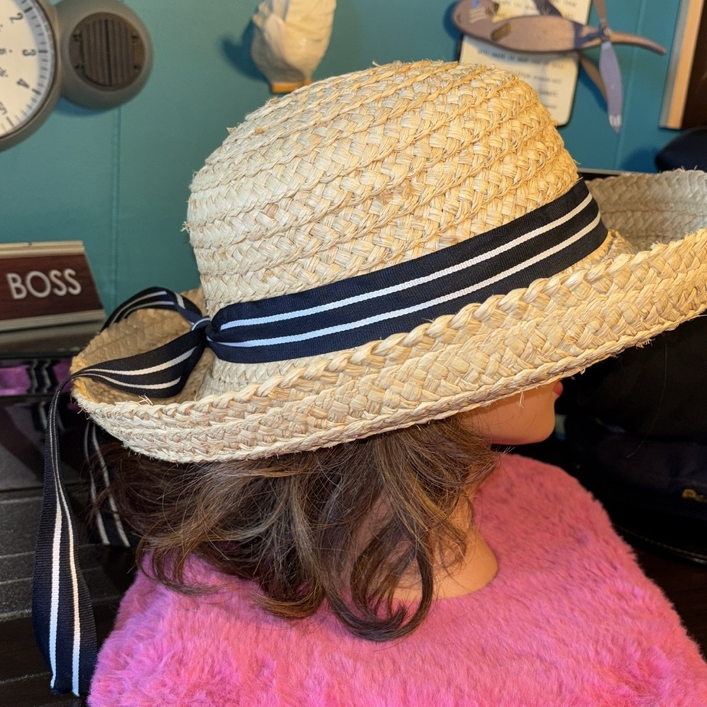 August Accessories Straw Hat with navy and white striped flowing off Briam ribbo